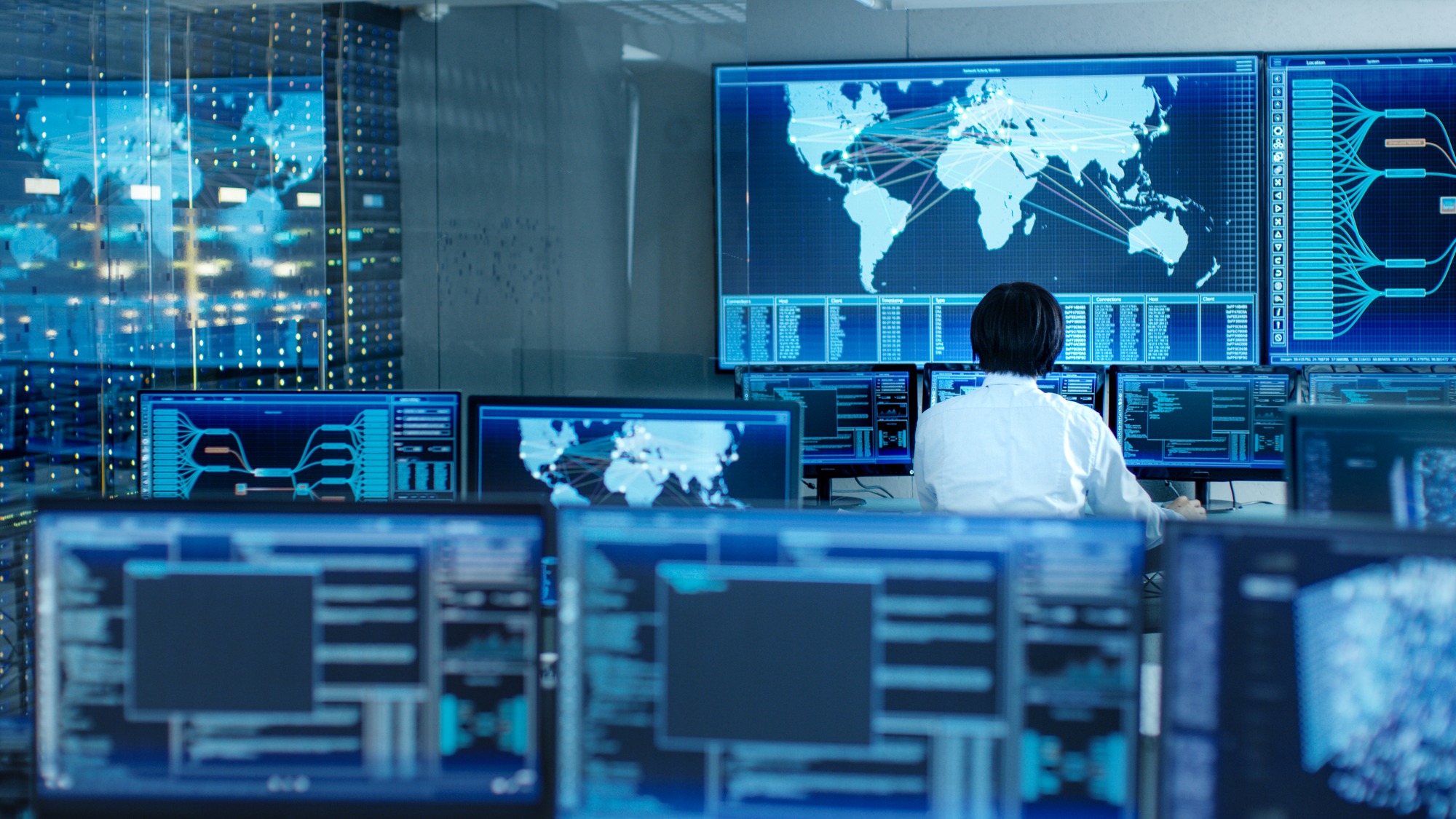 In the System Control Room Operator Sits at His Workstation With Multiple Displays Showing Graphics and Logistics Information.